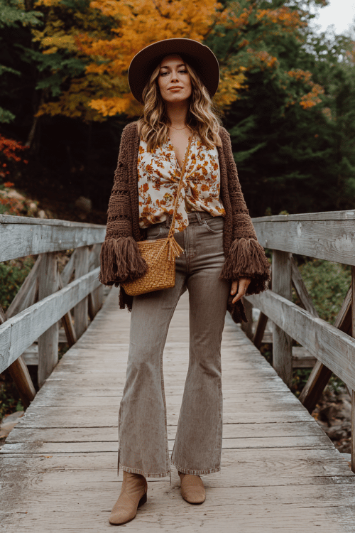 a woman wearing cropped flared jeans in a light vintage wash paired with a boho printed wrap blouse in warm amber florals, layered with a chunky oversized cardigan in chocolate brown