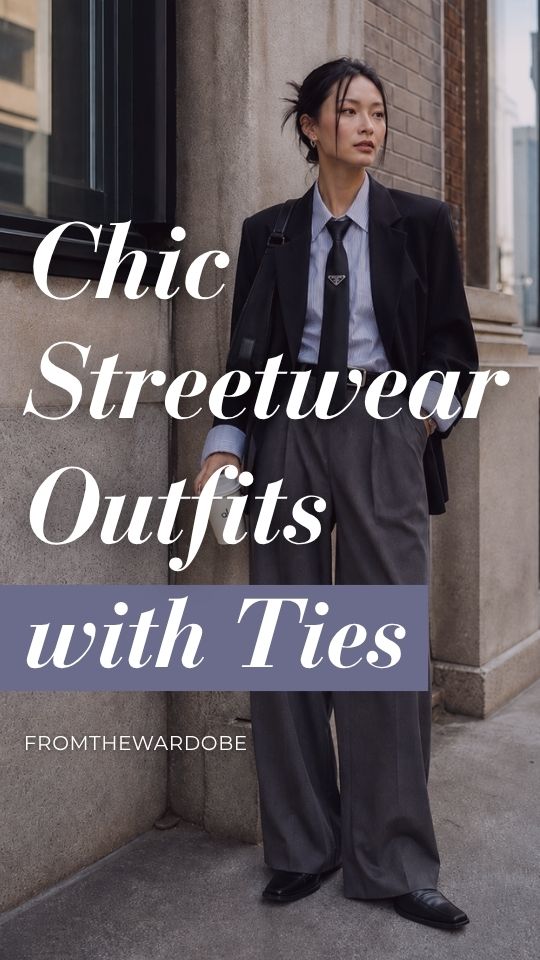 A woman wears a streetwear outfit with a tie, a blue button-down shirt, oversized black suit, and black loafers