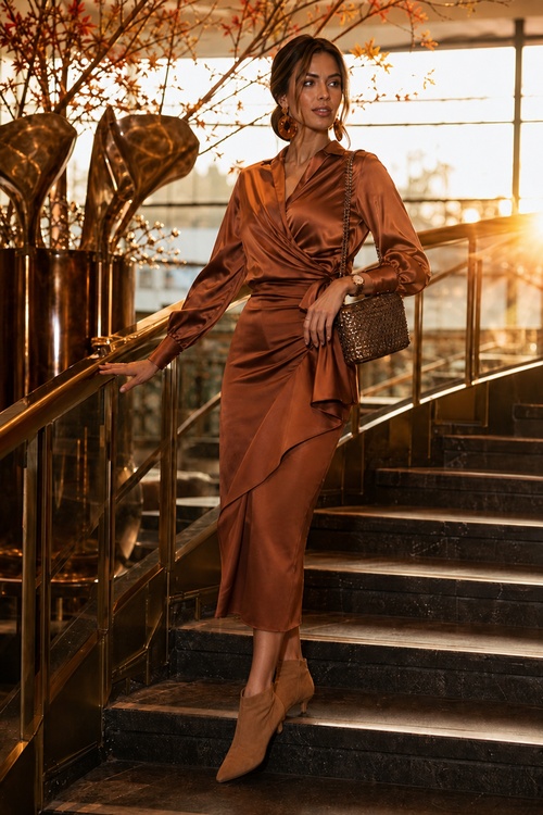 a woman wears a brown satin wrap dress with ankle boots and a metallic shoulder bag