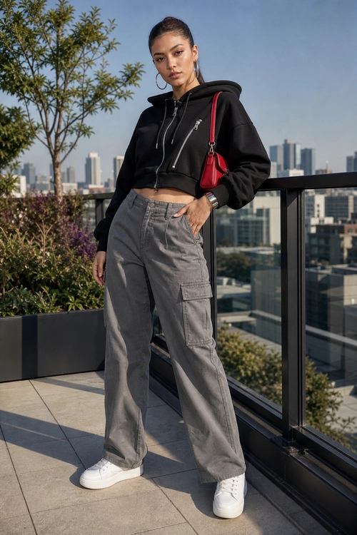 A black cropped hooded jacket styled with gray cargo pants, white sneakers, and a red shoulder bag.