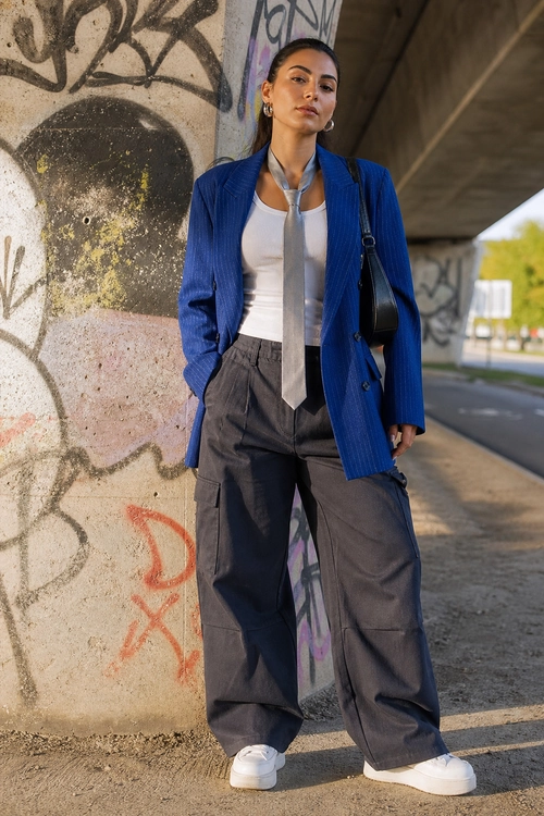 Blue Blazer and Wide-Leg Cargo Pants A woman wears a blue blazer over a white top with a gray tie, wide-leg cargo pants, white sneakers, and a black shoulder bag.