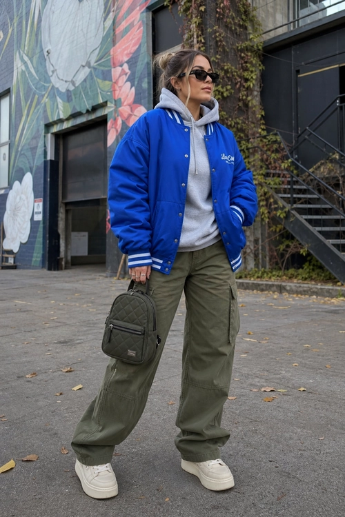 Blue Bomber Jacket and Cargo Pants Outfit A person wears a blue bomber jacket over a gray hoodie with olive cargo pants, white sneakers, black sunglasses, and a black quilted crossbody bag.