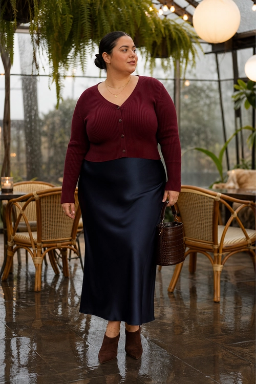 Burgundy Cardigan and Satin Skirt A burgundy ribbed cardigan is styled with a dark satin midi skirt, brown ankle boots, and a brown handbag.