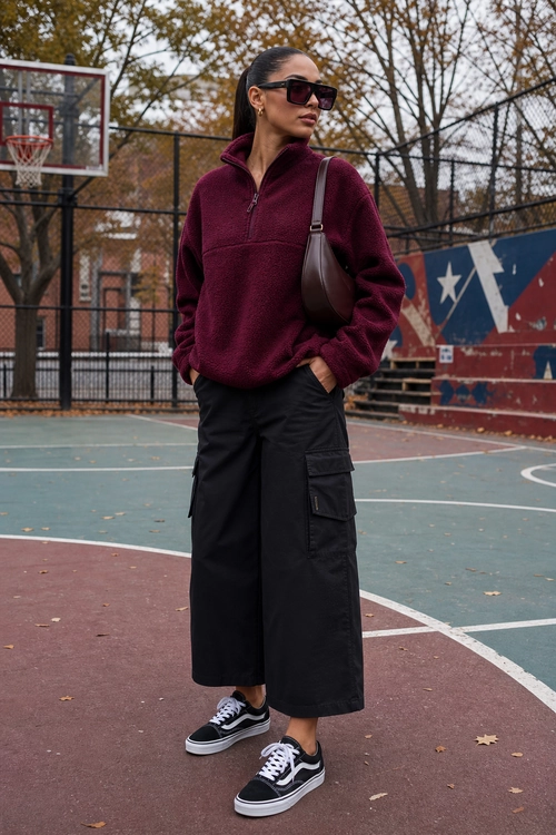 Burgundy Fleece and Black Cargo Pants A casual outfit featuring a burgundy quarter-zip fleece, black wide-leg cargo pants, black low-top sneakers, sunglasses, and a brown shoulder bag.