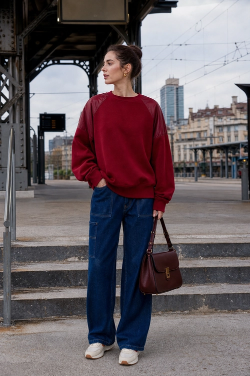 A casual outfit featuring a burgundy sweatshirt, dark blue wide-leg jeans, white sneakers, and a brown shoulder bag.