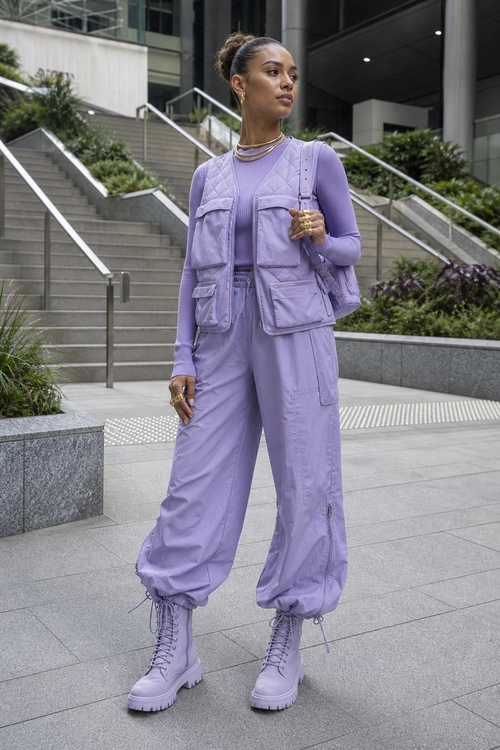 Lavender Utility Street Style Outfit A person wears a monochromatic lavender utility vest, long-sleeve top, cargo pants, combat boots, and shoulder bag outdoors.