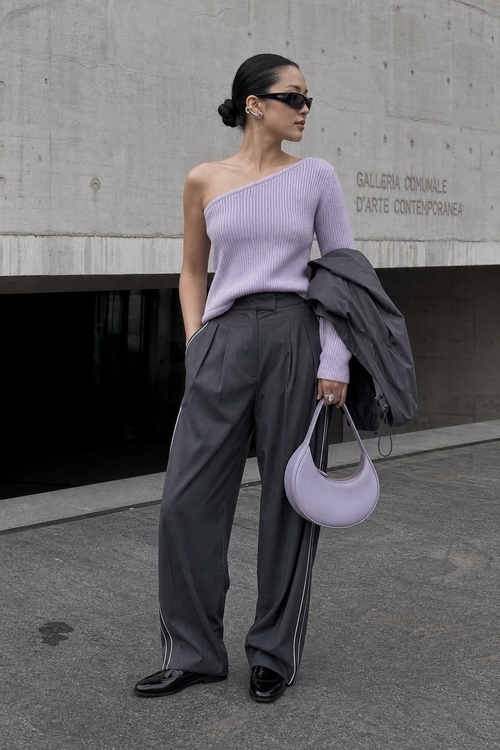 Lilac One-Shoulder Knit Outfit A lilac one-shoulder ribbed knit top styled with charcoal wide-leg trousers, a draped dark jacket, a lilac handbag, black sunglasses, and black loafers.