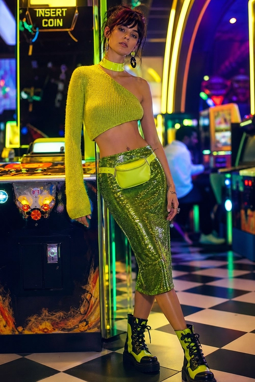 Lime Green Sequin Nightlife Outfit A lime green one-shoulder cropped knit top paired with a green sequin midi skirt, neon belt bag, and black platform lace-up boots.