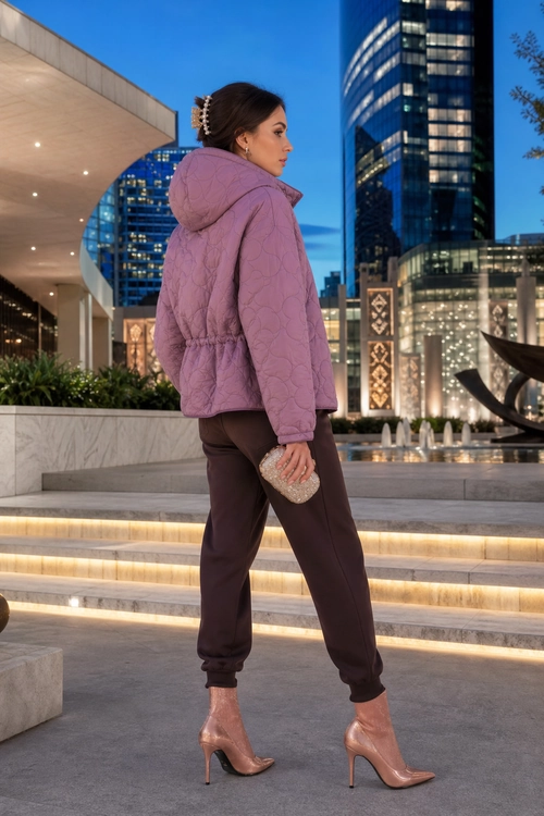 Mauve Quilted Jacket and Brown Joggers A woman wears a mauve quilted hooded jacket with dark brown jogger trousers, blush pointed ankle boots, and a small embellished clutch.