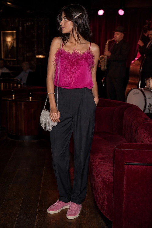 Pink Feather-Trim Cami Outfit A woman wears a bright pink feather-trim camisole with black trousers, pink sneakers, and a silver beaded shoulder bag.