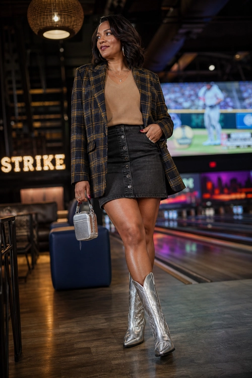 Plaid Blazer and Silver Boots A woman wears a plaid blazer with a tan top, black button-front mini skirt, silver cowboy boots, and a small metallic handbag.