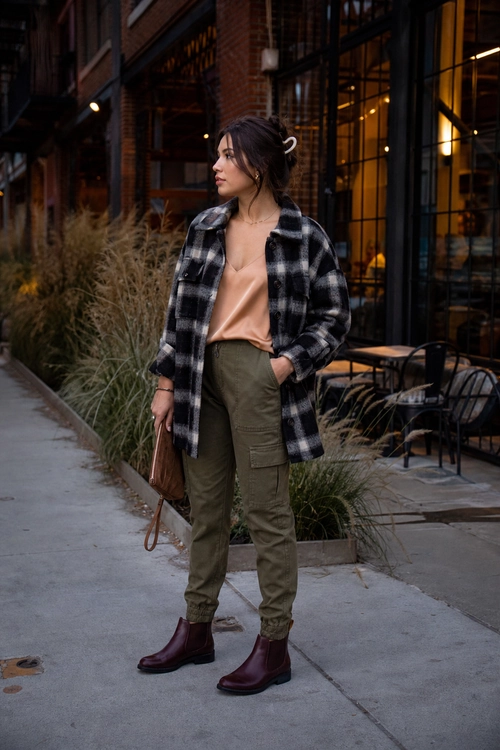 Plaid Shacket with Olive Cargo Pants A woman wears a black and white plaid shacket over a peach top with olive cargo pants and burgundy ankle boots.