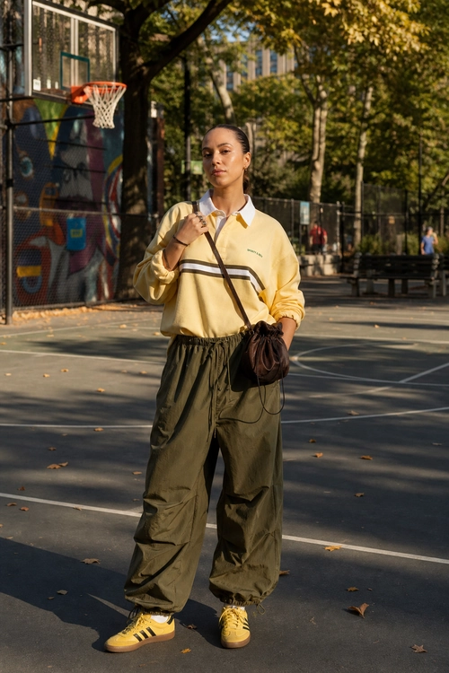 Yellow Sweatshirt and Olive Wide-Leg Pants A casual outfit featuring a pale yellow collared sweatshirt, olive wide-leg pants, yellow sneakers, and a brown crossbody bag.