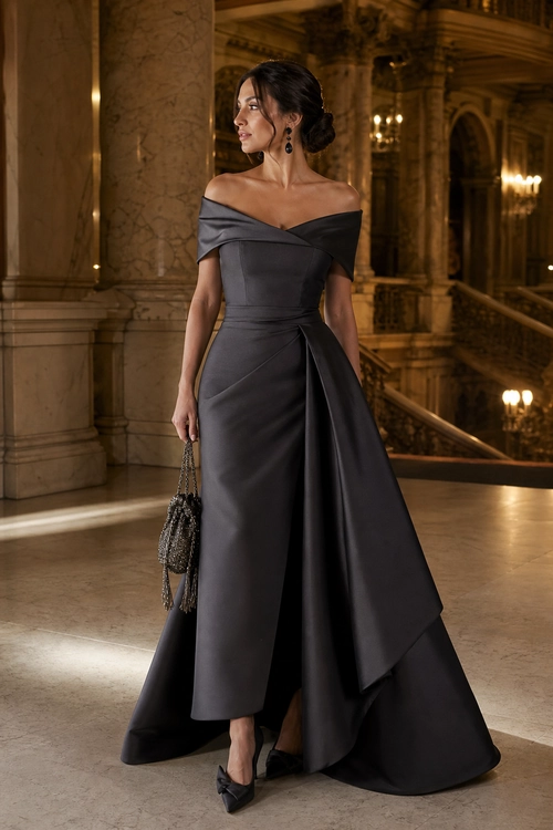 Charcoal Off-Shoulder Evening Gown Woman wearing a charcoal gray off-shoulder gown with a draped train, black pointed heels, drop earrings, and a beaded handbag.