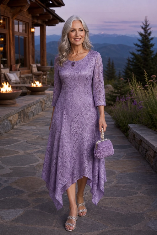 A woman wears a lavender lace dress with an asymmetric handkerchief hem, silver strappy sandals, a purple clutch, and a pendant necklace.