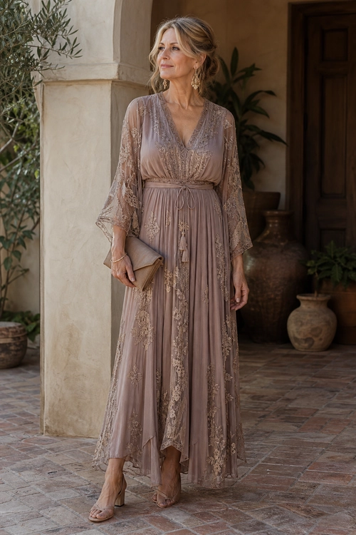Woman wearing a mauve lace-trimmed maxi dress with sheer sleeves, a matching clutch, drop earrings, and strappy heeled sandals.