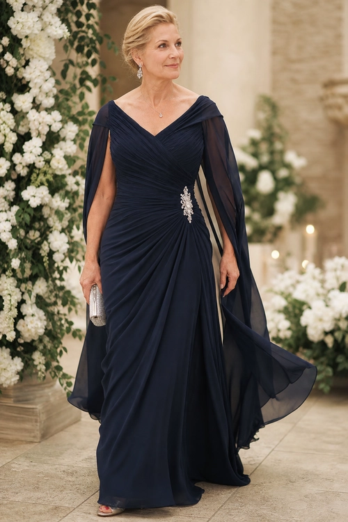Navy Draped Evening Gown A woman wears a floor-length navy gown with a ruched bodice, sheer draped sleeves, silver waist embellishment, and a metallic clutch.