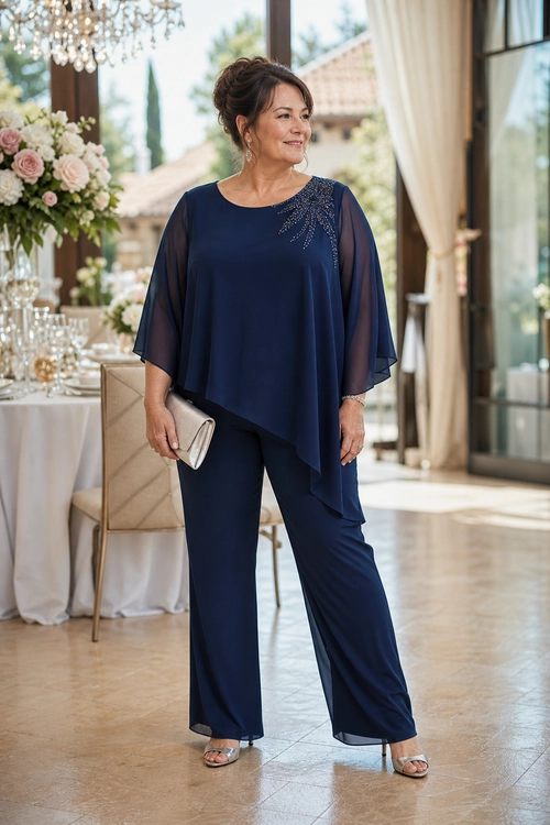 Navy Sheer-Sleeve Evening Outfit Woman wearing a navy tunic with sheer sleeves and embellished neckline, matching wide-leg trousers, a light clutch, and metallic sandals.