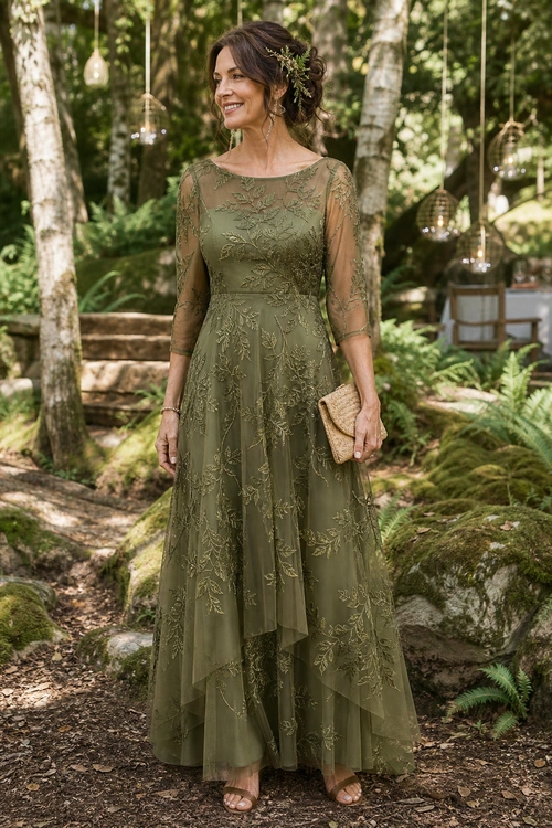 Olive Green Embroidered Maxi Dress Woman wearing an olive green embroidered maxi dress with sheer sleeves, nude sandals, and a woven clutch in a forest setting.