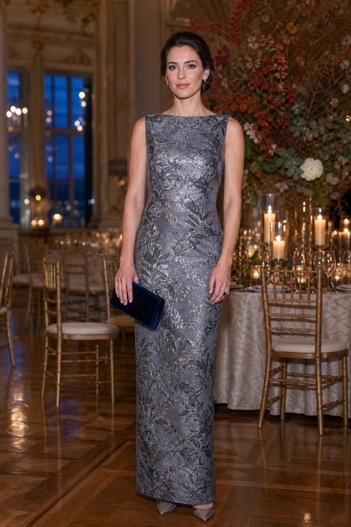 Silver Floral Brocade Evening Gown A woman wears a sleeveless silver-gray floral brocade gown with a navy clutch and pointed heels.