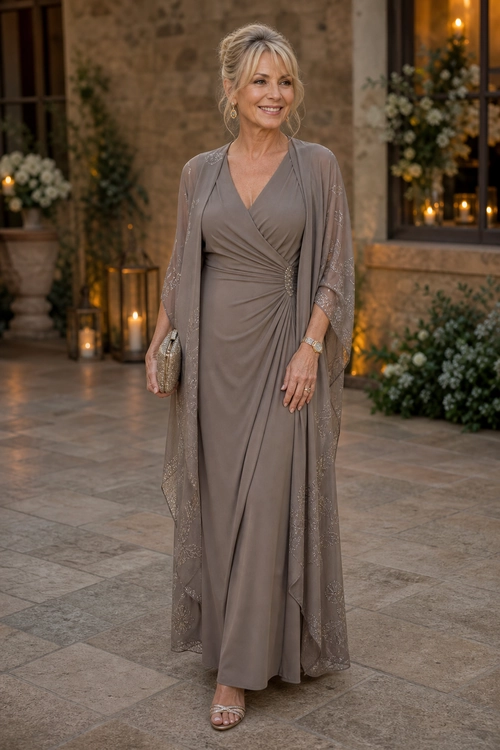 A woman wears a taupe draped floor-length dress with a sheer embellished overlay, clutch, and strappy sandals.